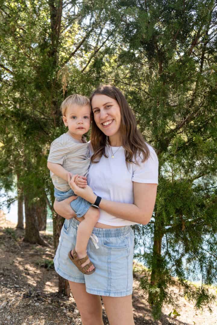 Mom holding her toddler boy, smiling at the camera.
